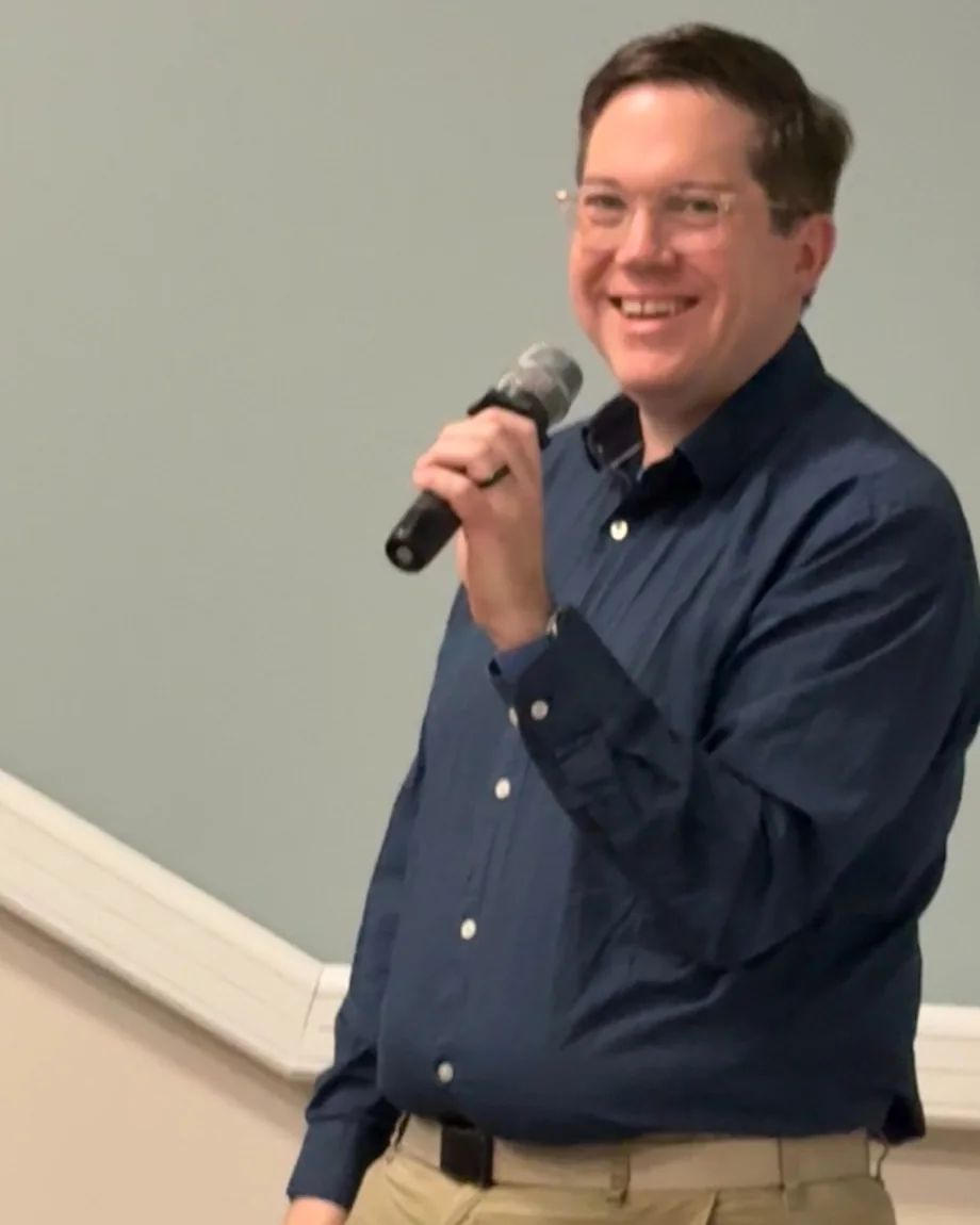 Yair Walton speaking to a room, holding a microphone